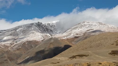 Snowy mountain range against a blue sky with clouds