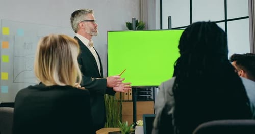Businessman explaining presentation on green screen for attantive successful team of colleagues