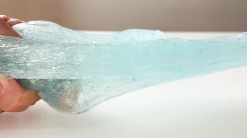 A Woman or Teenage Girl Relieves Stress By Playing with Blue Slime Stretching and Squeezing It on a