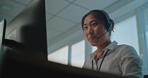 Asiatische Spezialistin für technischen Kundensupport spricht über ein Headset, das am Computer funktioniert
