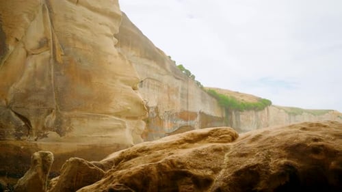 Tilting up handheld shot of a cliff wall by the coast in New Zealand