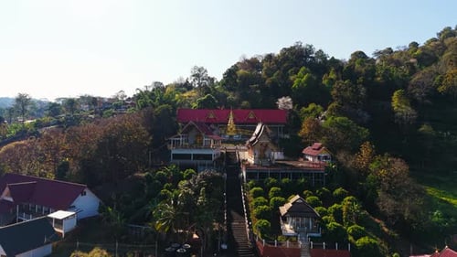 Buddhist Temple Perched on Hillside Surrounded By Verdant Landscape in Northern Thailand