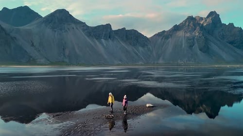 Stokksnes Cape and Vestrahorn Mountain Iceland with Adventurers Exploring Serene Mountain Reflection