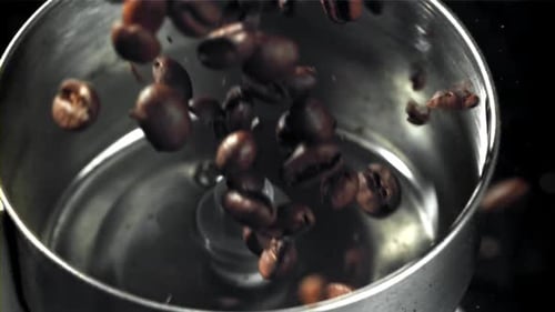 Die Kaffeebohnen fallen in die funktionierende Mühle, gefilmt mit einer Hochgeschwindigkeitskamera mit 1000 Bildern pro Sekunde