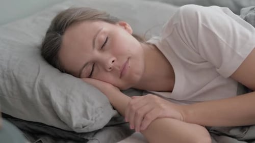 Young Woman Sleeping while Lying on Side in Bed