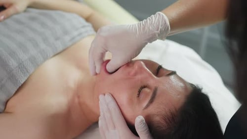 High Angle Shot Of Client Receiving Fingernail Dip And Cheek Massage In Clinic