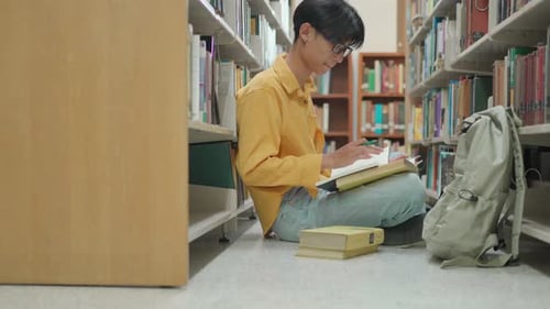 Young Asian University Student reading in a library