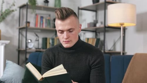 Man Reads a Book on a Couch at Home