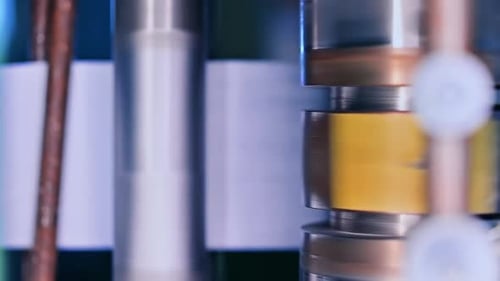 Diaper producing factory. Shiny metal roller spinning around. Blurred shaft at the backdrop.