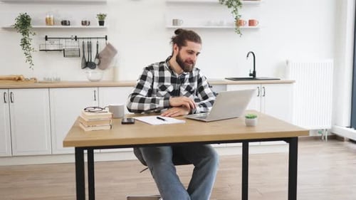 Young Man Attends Video Call at Kitchen Table