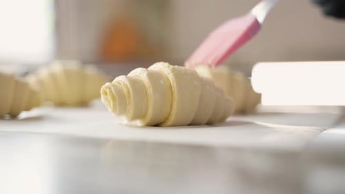 Applying Egg Wash to Croissant Dough for Baking