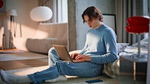 Studying Guy Sitting Floor Using Laptop in Sunny Bedroom Man Finishing Working