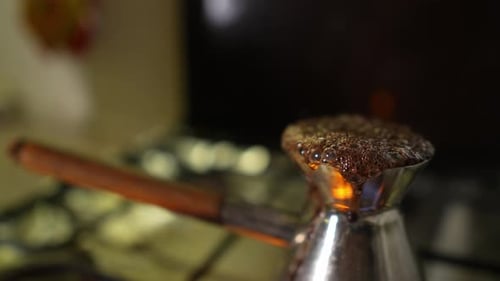 Slow Motion of the Coffee Boiling Over the Cezve Standing at the Gas Stove Filmed in Closeup