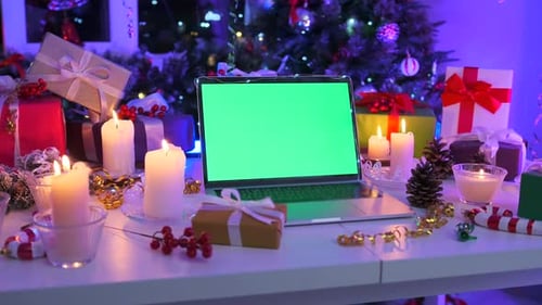 Static laptop with chromakey screen in cozy workshop decorated with burning candles and gift boxes