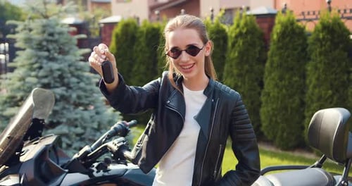 Close-up. Confident woman buy new motorcycle. Smiling caucasian girl holding new sport bike keys