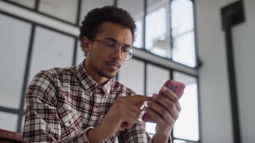 Man Uses Smartphone While Sitting Indoors