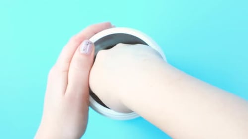 Chocolate protein powder in scoop and plastic jar on blue background, top view.