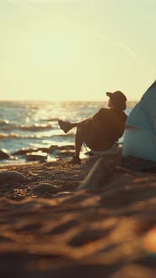 Camper Relaxing in Chair on Beach at Sunset