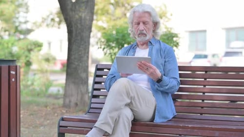 Senior Adult Using Tablet on Park Bench