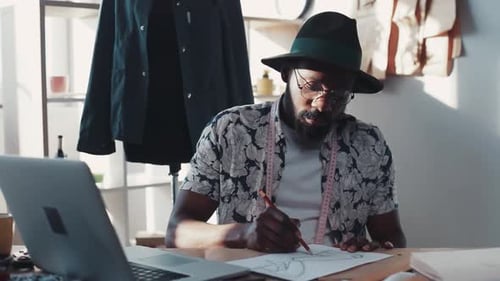 Man Designs Fashion at Desk with Laptop