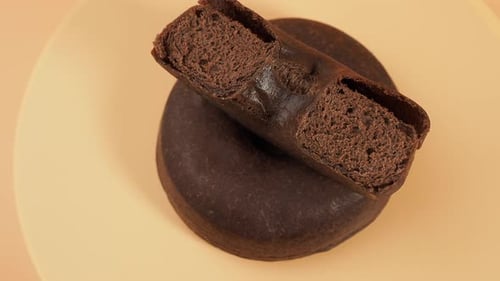 Rotating dark vegetarian donut on an orange background.