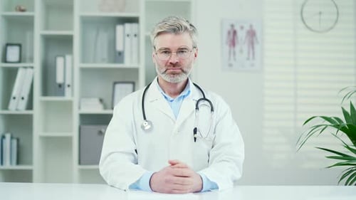 Mature Doctor in White Lab Coat in Office