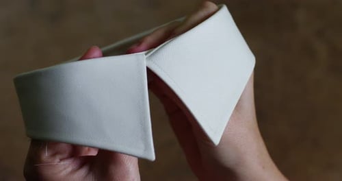 La main d'une jeune couturière fixe le col blanc d'une chemise avant de la coudre et contrôle le