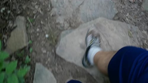 Close up of feet as hiker walks down rocky steps on the trail.