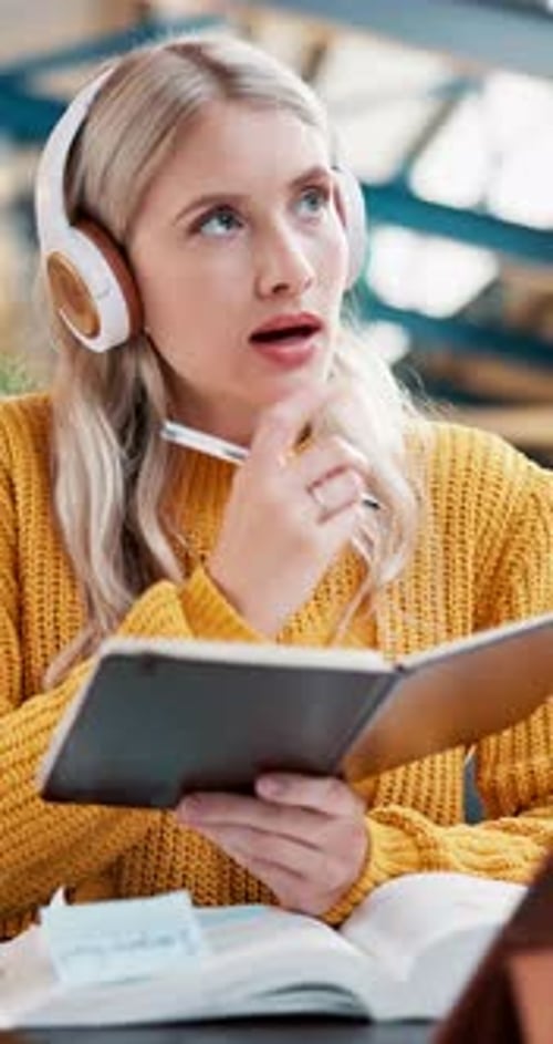 Focused Student Writing Notes with Headphones On