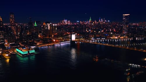Drone footage over the East River approaching the Manhattan Bridge at night.