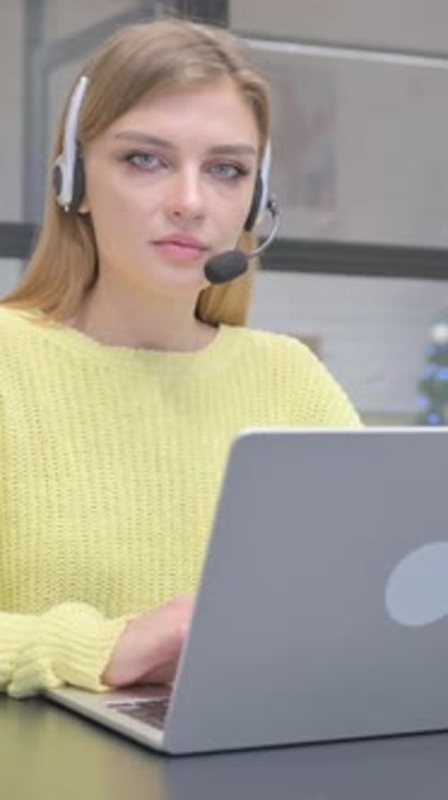 Female Call Center Employee with Headset Smiling at Camera, vertical video