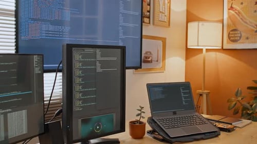 Bildschirme mit Computercode auf dem Schreibtisch eines Entwicklers, der von zu Hause aus arbeitet