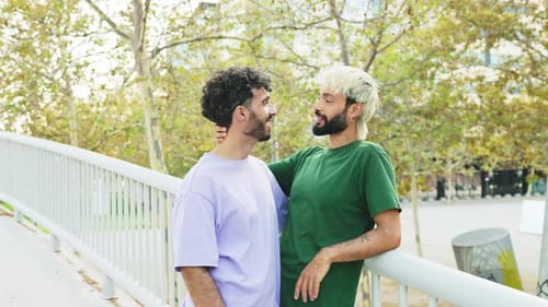 Young gay couple in love talking in a public park in the city, hugging each other