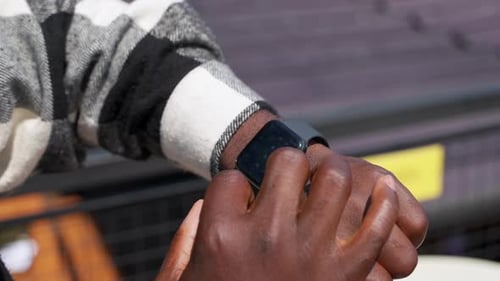 African American Man is Checking Weather on Screen of Smartwatch Closeup View
