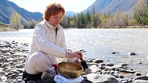 Woman Performing a Sound Ritual with a Tibetan Singing Bowl By the Altai River Concept of Feminine