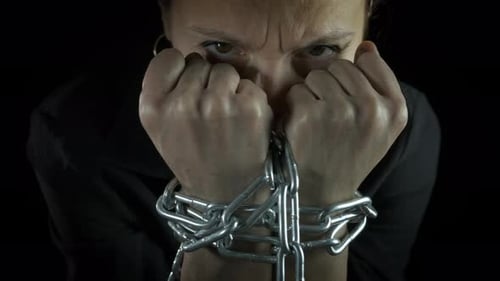 Mulher escrava com mãos acorrentadas dentro de casa