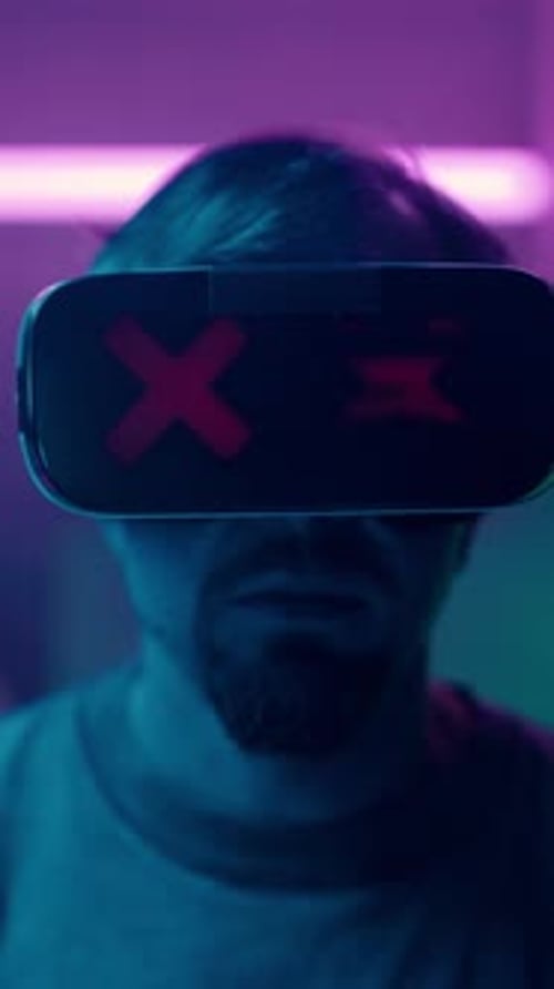 Man Removing VR Headset in Dark Blue Lit Room