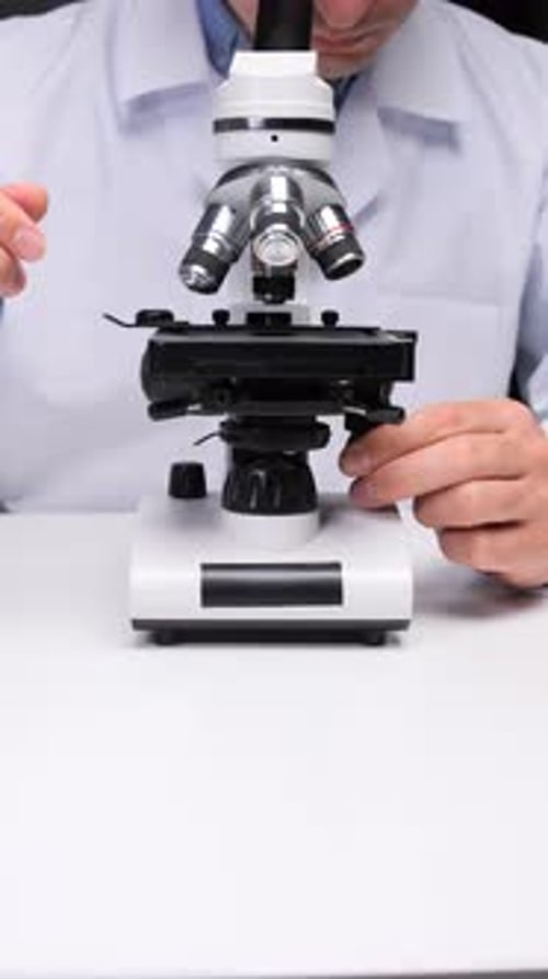 Man Adjusting Microscope in Laboratory Setting