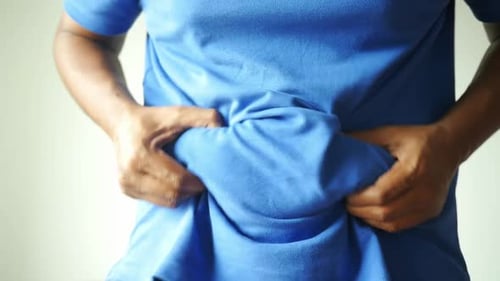 Man Pinches Stomach in Blue Shirt Close Up