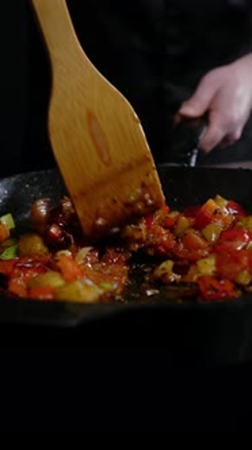 Chef stirs vegetables in a hot pan