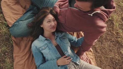 Young Couple Relaxing Together Outdoors on Picnic Blanket
