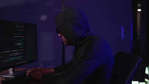 Man Working at Computer Wearing Hood and Shades