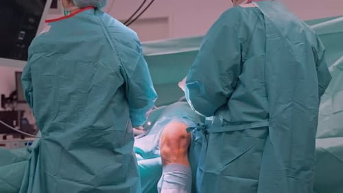 Surgeons Team Preparing Patient and Instruments For Knee Arthroscopy Surgery in Modern Hospital