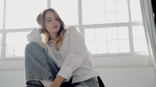 Stylish Woman in Jeans and White Shirt Sitting and Posing on Camera