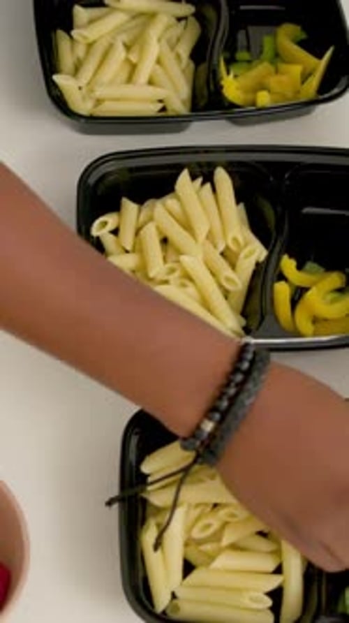 La main apparaît et tend la main pendant que le cuisinier à la maison prépare les contenants de préparation des repas et remplit les compartiments