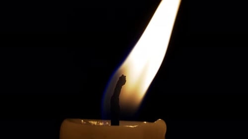 Die flackernde Flamme einer Kerze in einem dunklen Raum schafft eine ruhige Atmosphäre