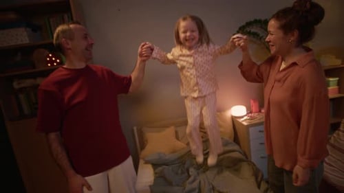 Playful Family Jumping on Bed Together at Home