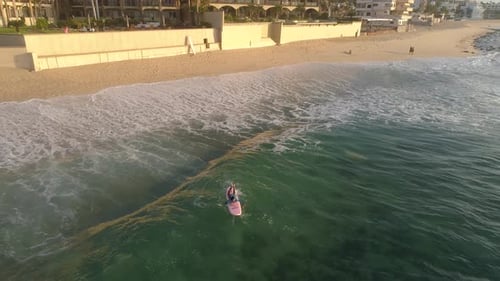 Aerial Shot of a Young Female Surfer Struggling to Paddle Out Into The Ocean in Los Cabos