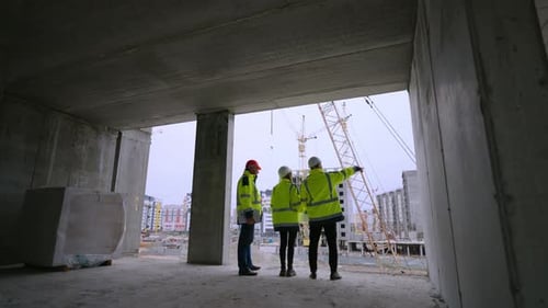 Três engenheiros civis da empresa de desenvolvimento estão observando a visão traseira do canteiro de obras