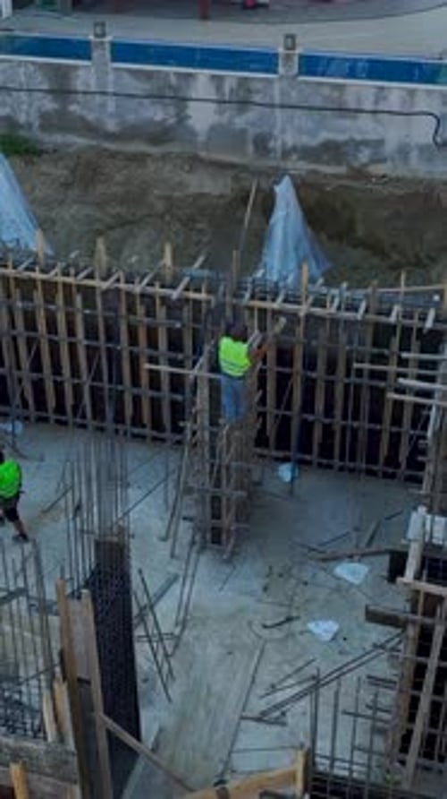 Vertical Video Engineers Guide Workers Shaping Rebar and Pouring Concrete for HighQuality
